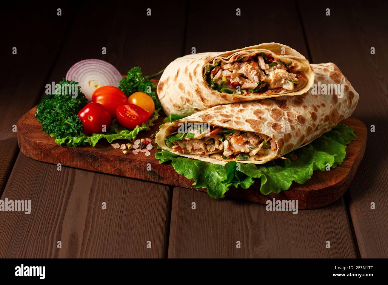 Shawarma, roll in lavash , grilled meat, with vegetables, sandwich , on a wooden brown Stock Photo