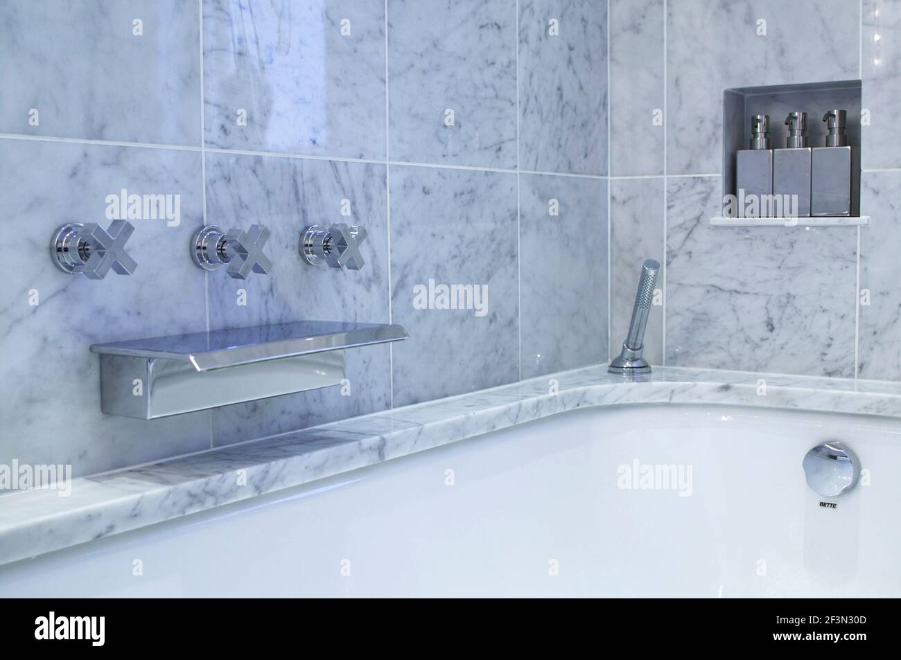 Chrome tap fitting set in marble tiles above bathtub Stock Photo Alamy