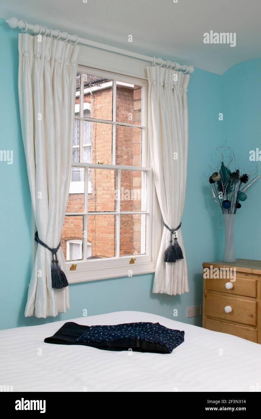 Modern bedroom, detail with bright blue walls and white curtains Stock Photo