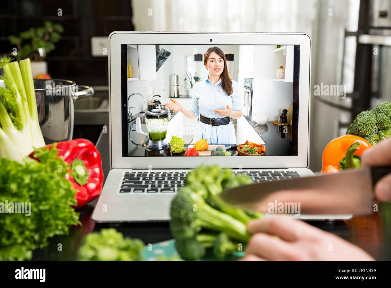 Beautiful happy woman streaming broadcast video blog about tasty and healthy food from home kitchen. Healthy lifestyle and social media. Man watching Stock Photo