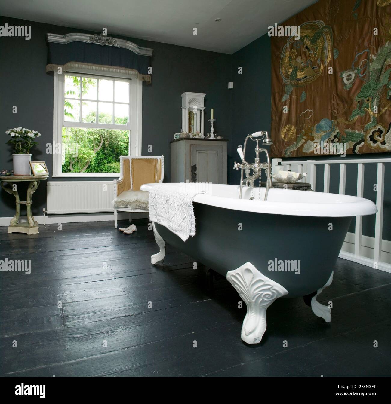 Freestanding bathtub in centre of grey bathroom in UK home Stock Photo