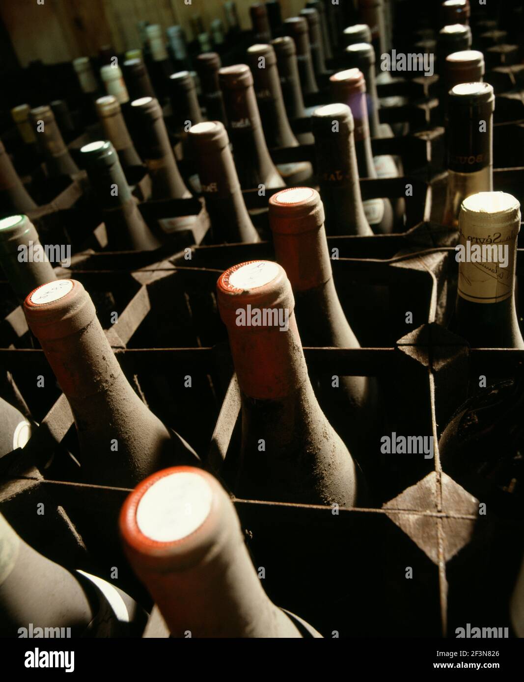 Wine bottles stored on side in rows. Dusty neck and cork ends. Metal