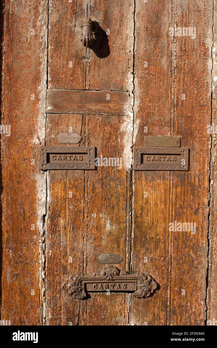 Old wooden doors with traditional letterboxes and ornate door knockers are commonplace in Porto, Portugal. Stock Photo