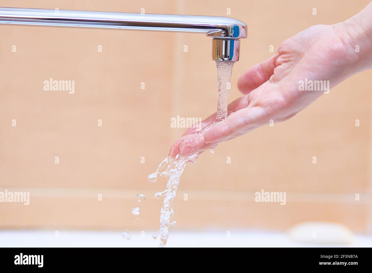 A woman's hand under the running water from the tap. Stock Photo