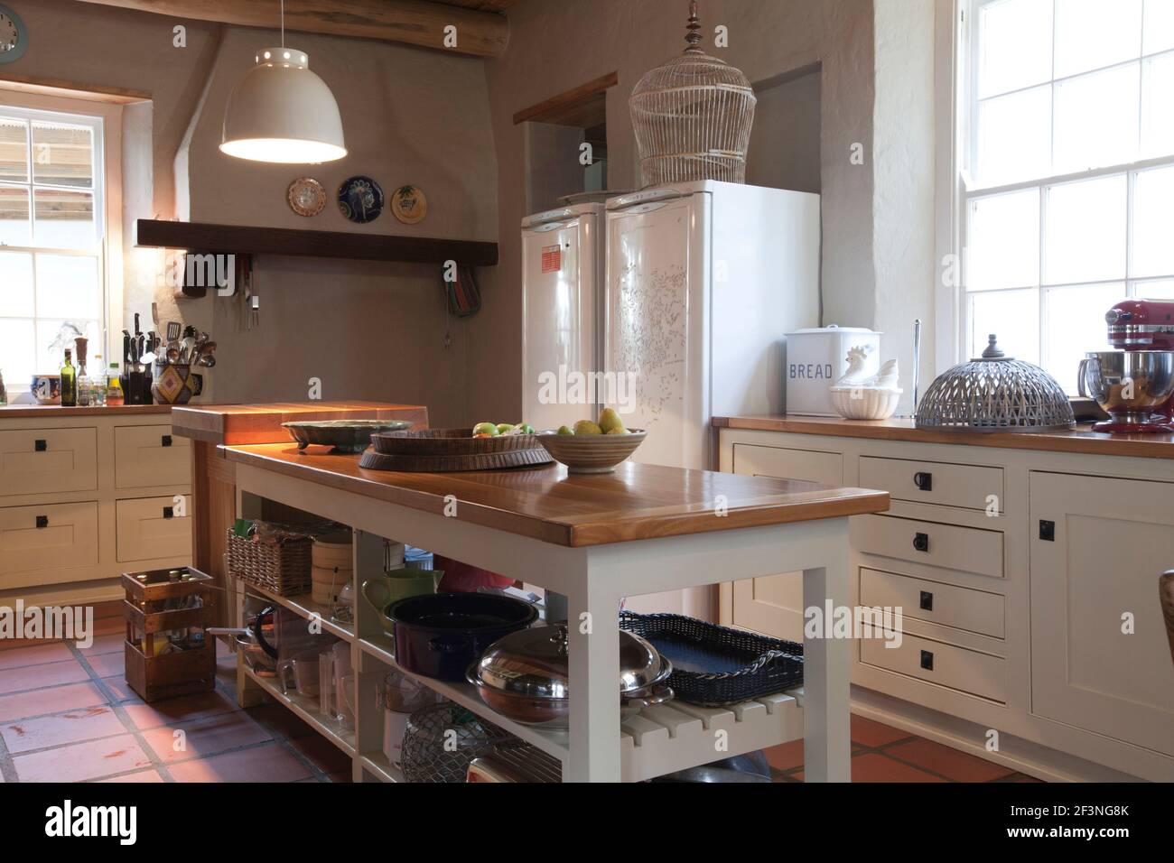 Farm style kitchen with wooden island displaying various pots Stock Photo