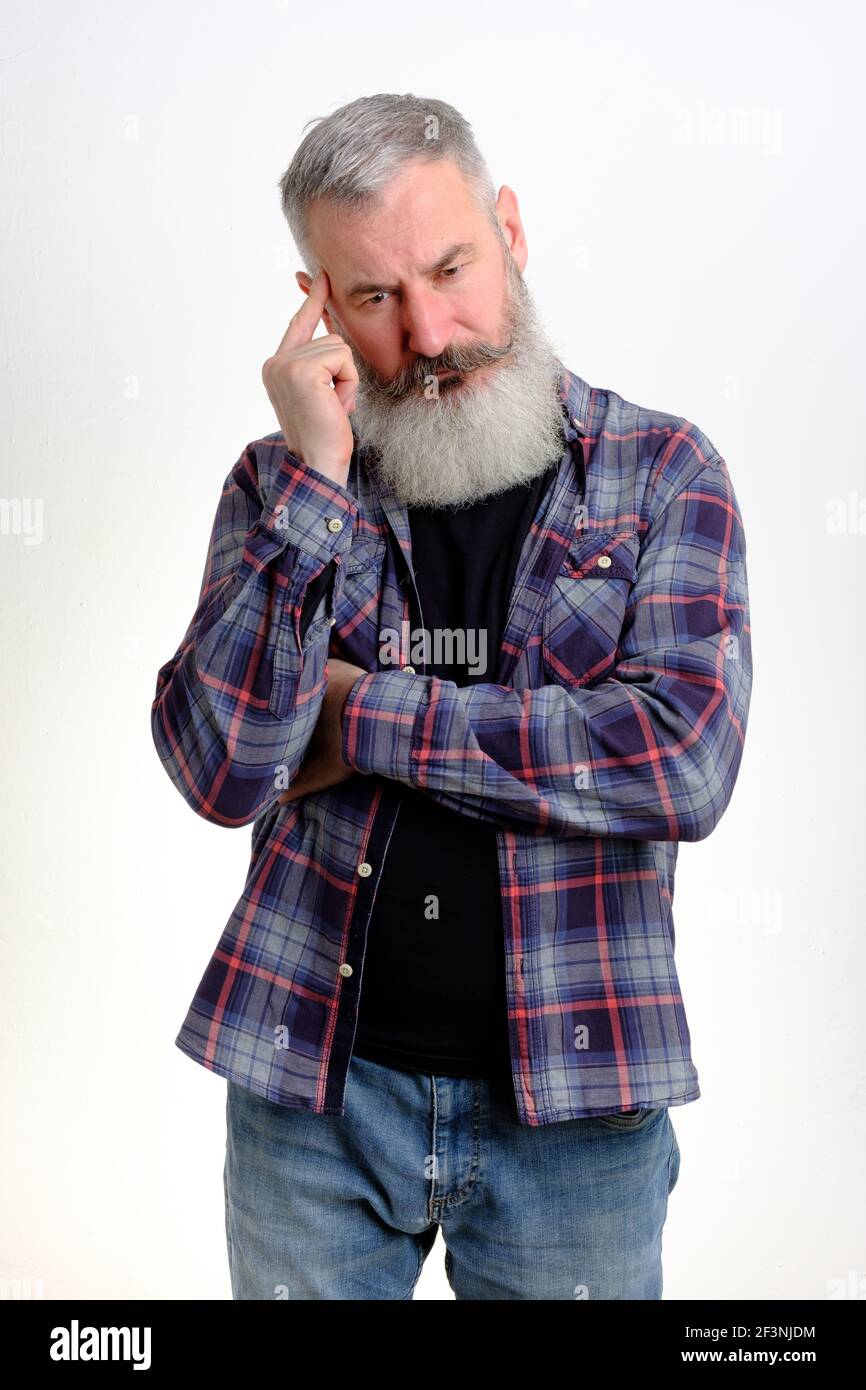 Studio portrait of pensive mature bearded man dressed in jeans and plaid shirt, looking worried, thinking about problems, white background Stock Photo