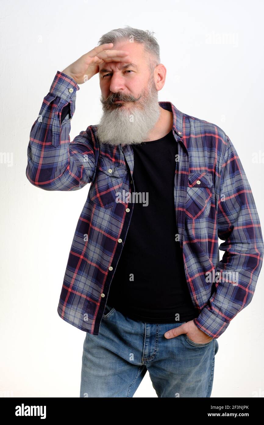 Studio portrait of mature bearded man who puts hand to forehead and looks aside, searching concept, look into future, white background Stock Photo