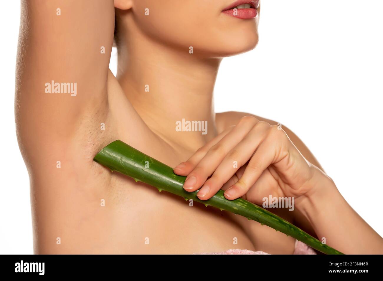 Young shirtless woman posing with a leaf of aloe vera on her armpit on  white background Stock Photo - Alamy