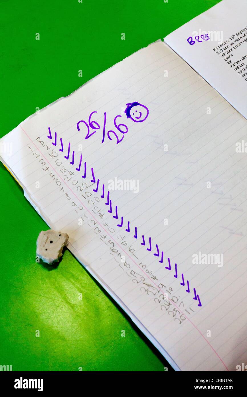 Close up view of primary school exercise book with answers to a mathematics test showing full marks. Stock Photo