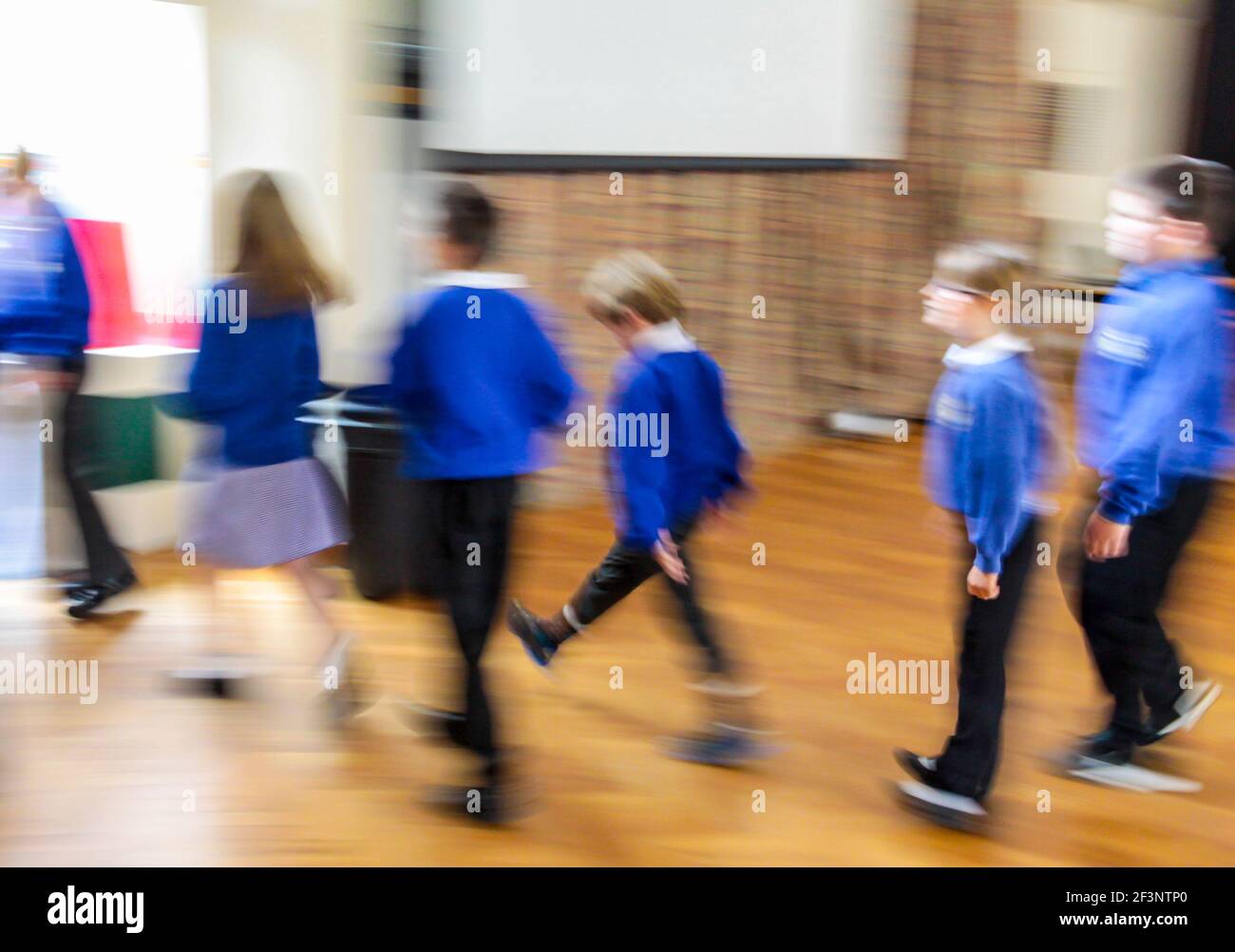 Group of primary school children in school uniform making their way back to the classroom after a break in the lesson with motion blur effect. Stock Photo
