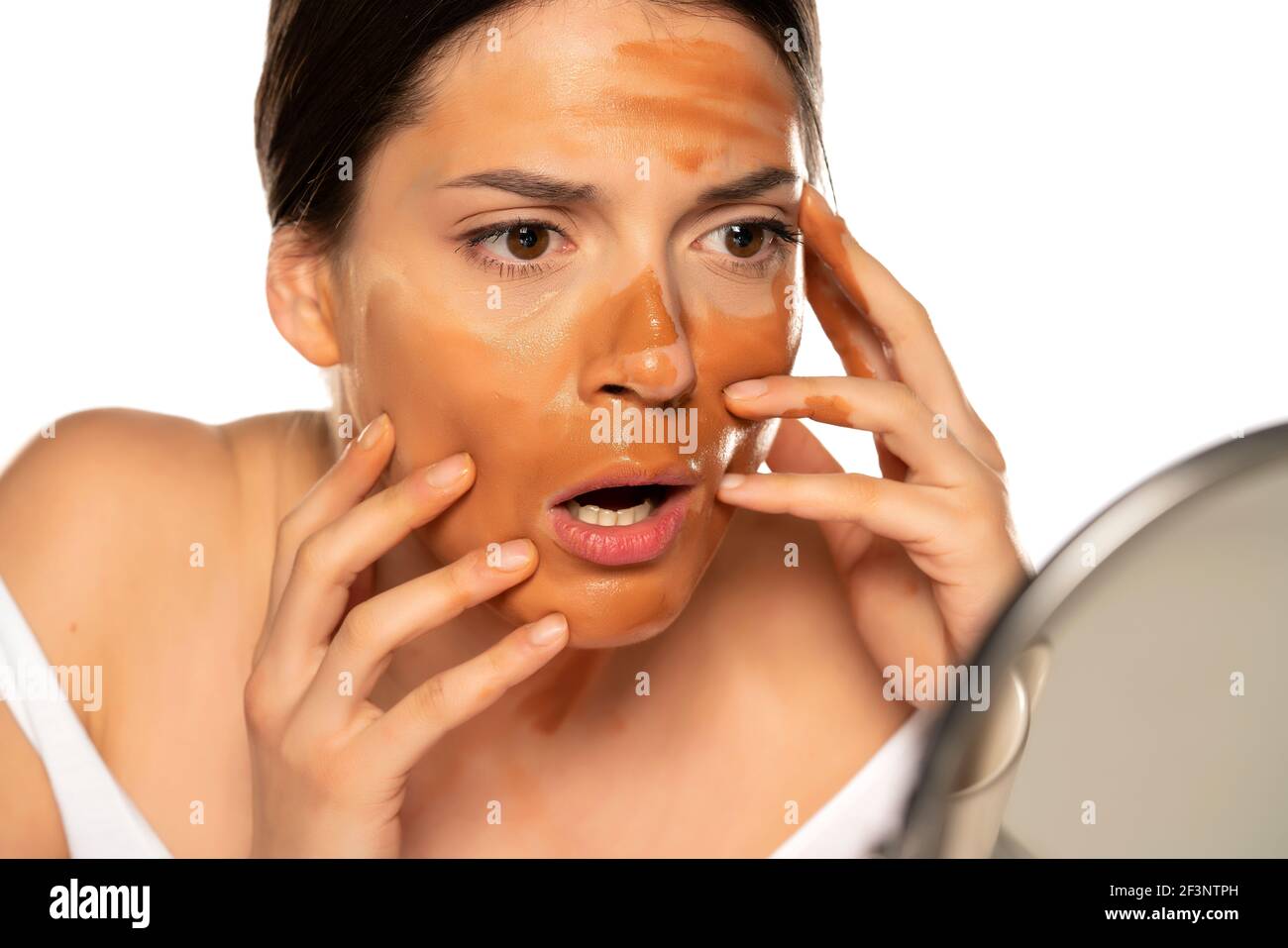xJYoung shocked woman with wrong makeup base on her face on white background Stock Photo
