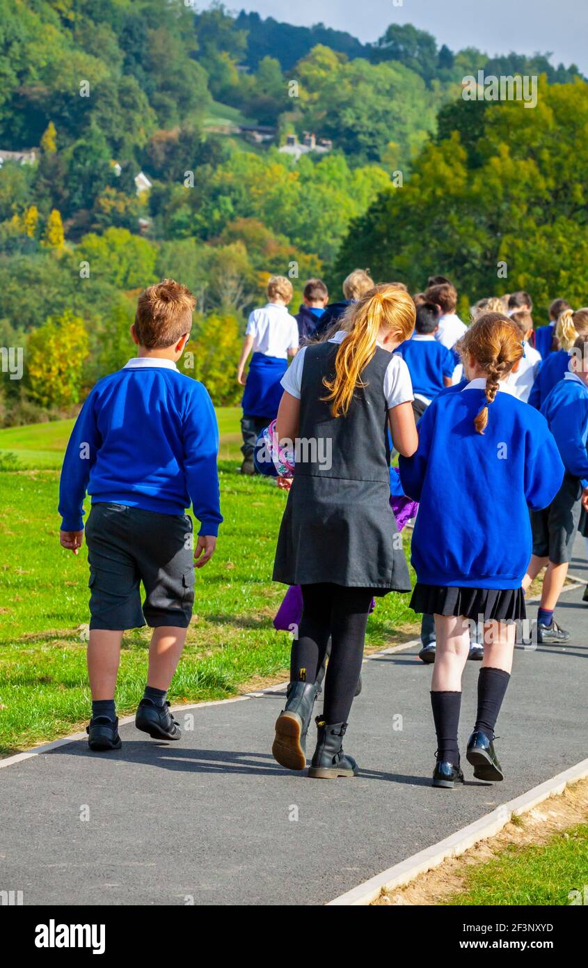 Group of primary school children in school uniform making their way back to the classroom after a break in the lessons. Stock Photo