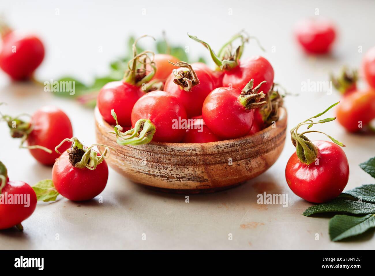 Fresh rosehips berries in small wooden bowl Stock Photo