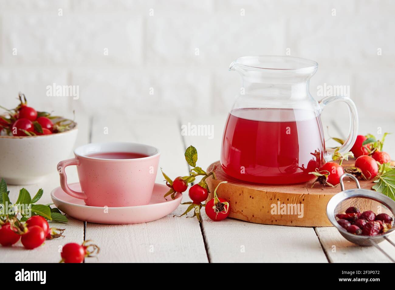 Cup of rose hip tea and fresh rose hips beside it Stock Photo