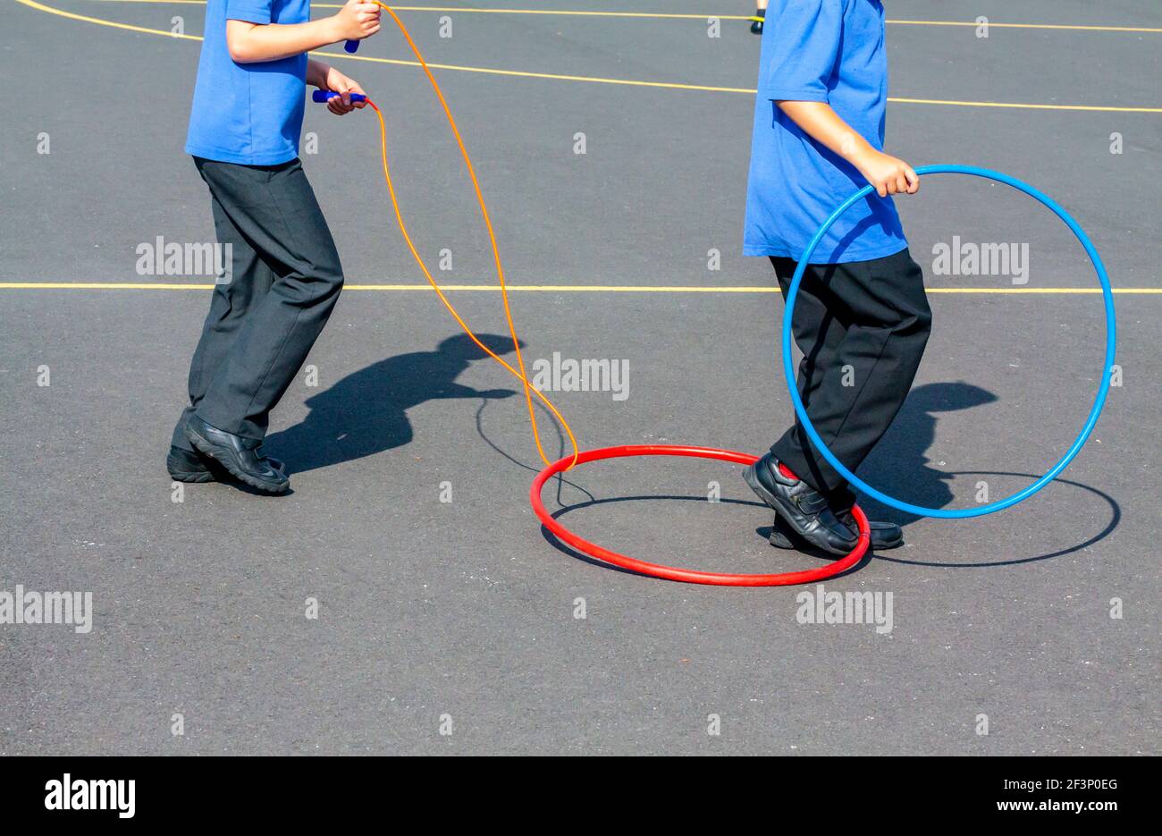 Primary school children playing with hoops outside in a school playground during a break from lessons. Stock Photo