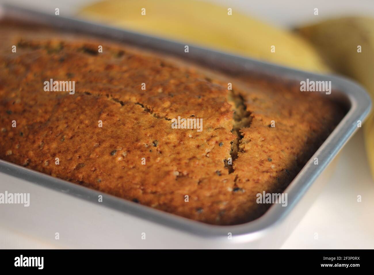 Home baked whole wheat ripe plantain cake. It is also called ripe plantain bread. Full loaf inside the loft tin. Shot on a white background Stock Photo