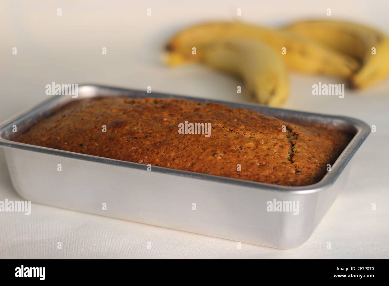 Home baked whole wheat ripe plantain cake. It is also called ripe plantain bread. Full loaf inside the loft tin. Shot on a white background Stock Photo