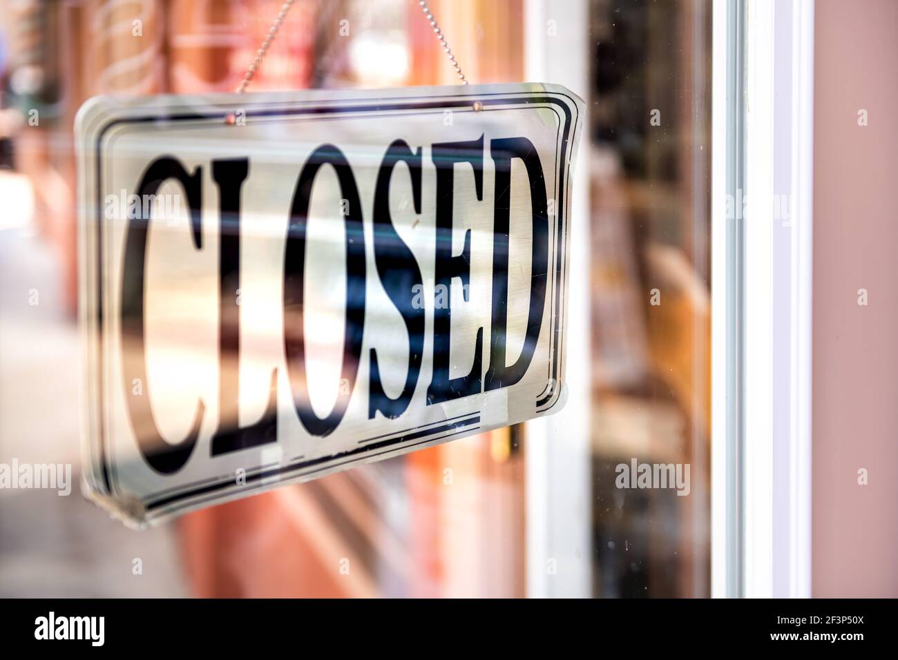 Closeup of closed white and black hanging sign on door of store retail shop business through glass window door Stock Photo