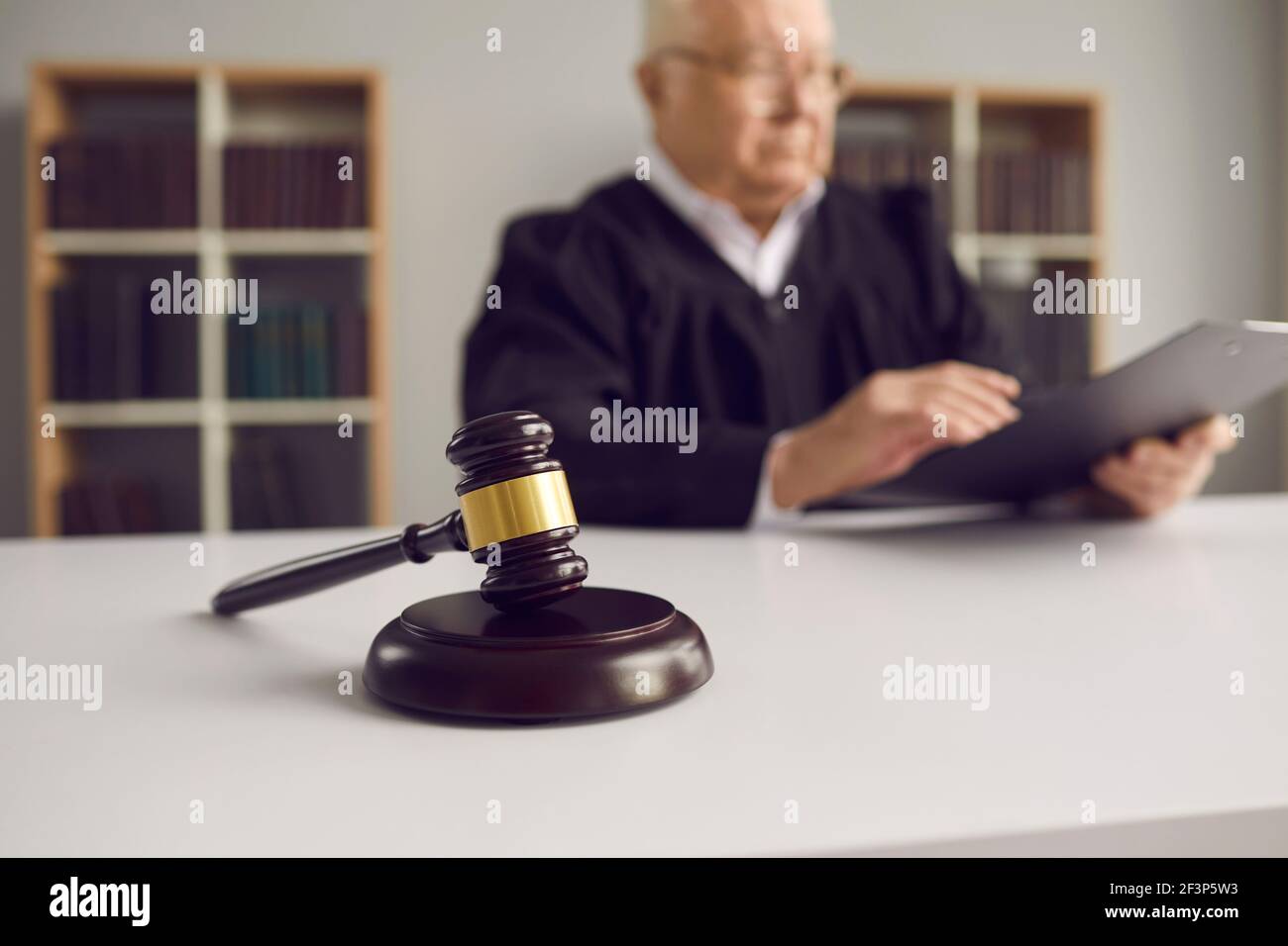 Close-up of a wooden gavel placed on sound block on judge's table in courtroom during court hearing. Stock Photo