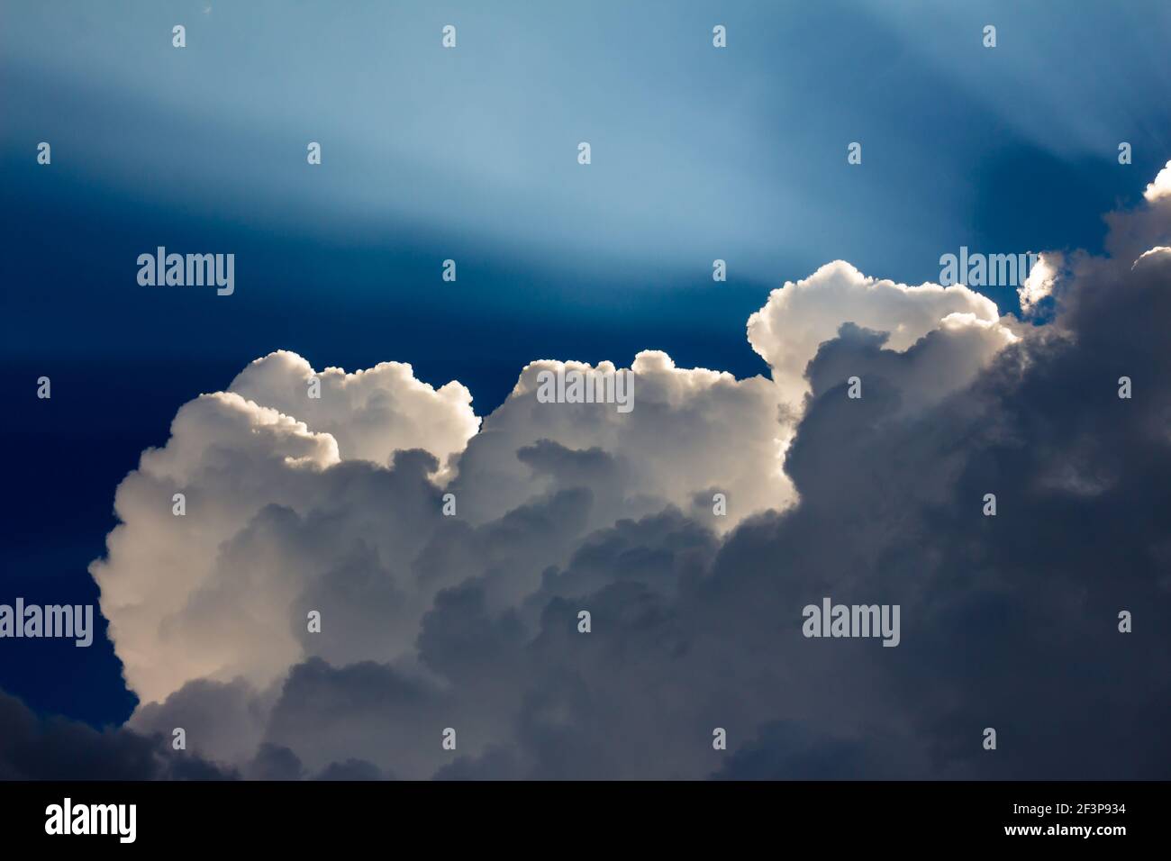 Glowing sun rays behind fluffy white cloud Stock Photo