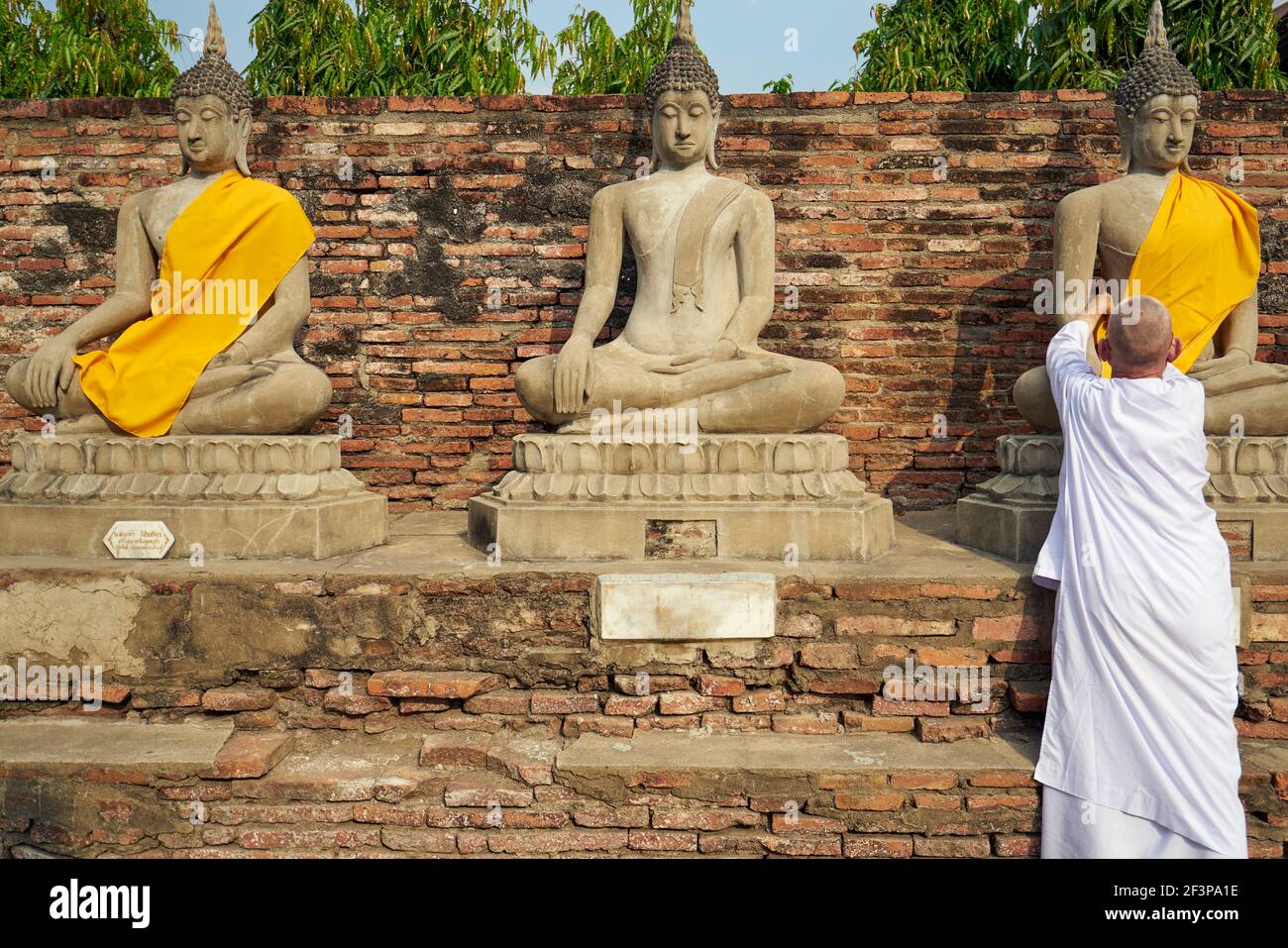 Buddhist Nun dressing Buddha statue at Wat Yai Chai Mongkol, Ayutthaya, Thailand Stock Photo