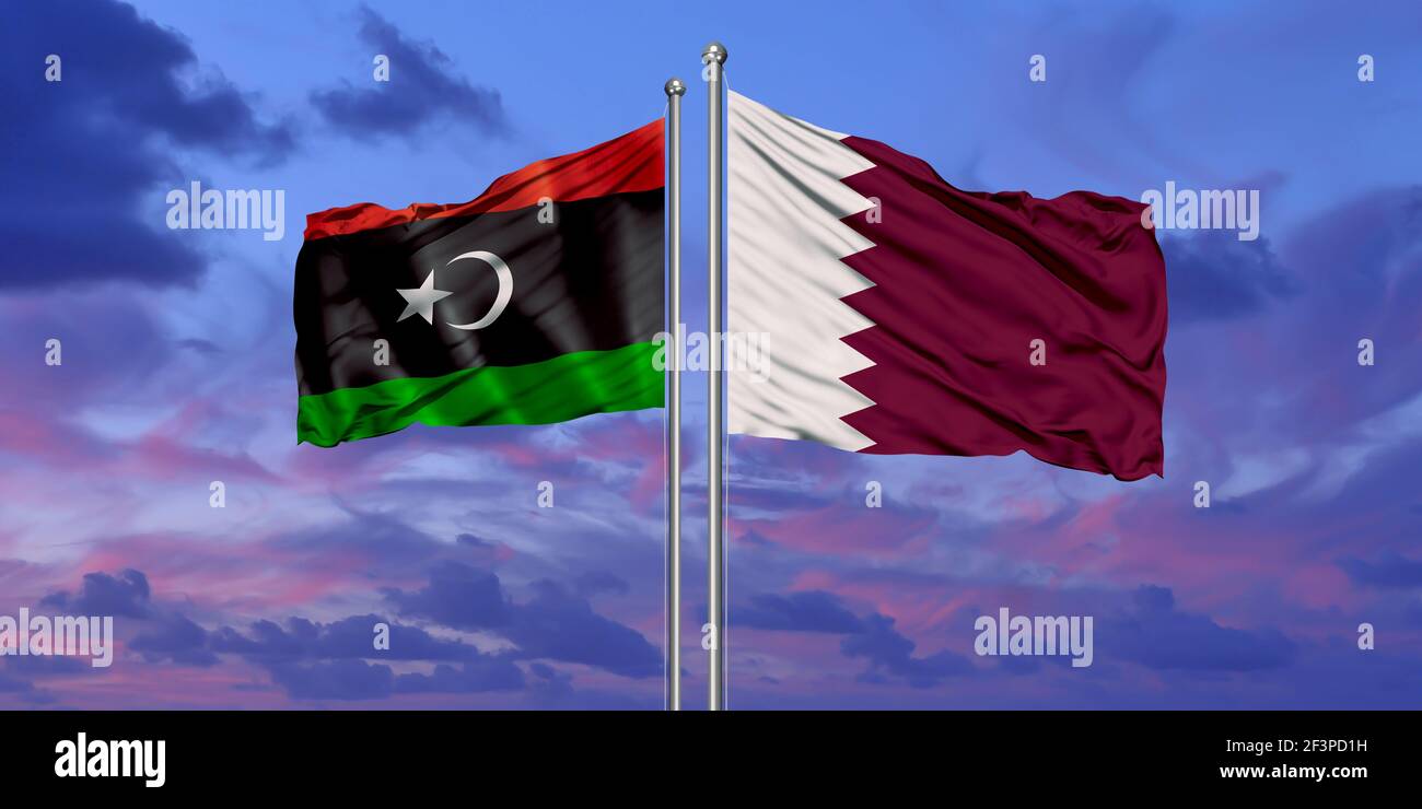 Qatar and Libya two flags on flagpoles and blue cloudy sky Stock Photo