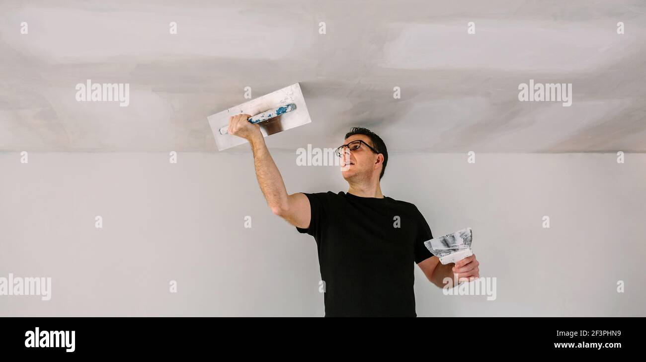 Plasterer smoothing plaster ceiling with the trowel Stock Photo