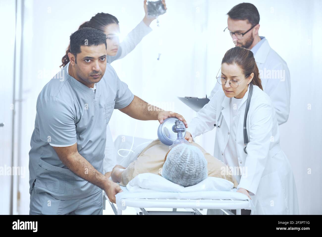 Doctors putting an oxygen mask on patient and pushing gurney stretcher bed in operating room Stock Photo