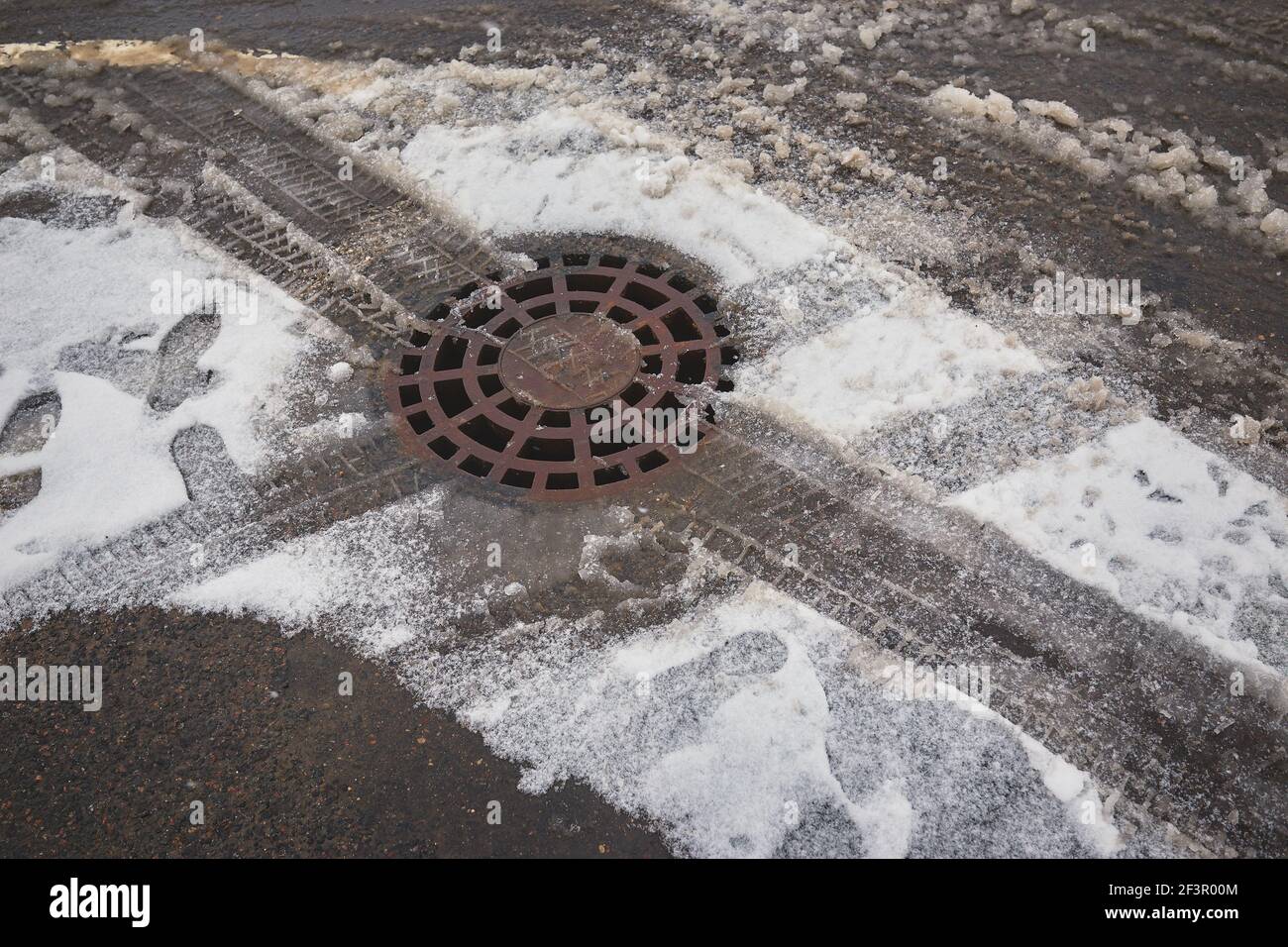 Contaminated the snow melts against the background of the drain into the storm sewer Stock Photo