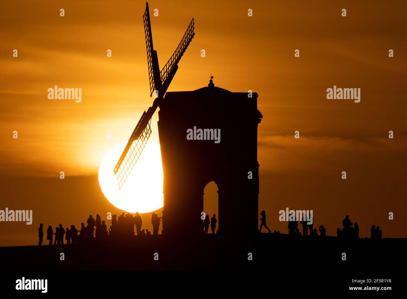 Groups of people watch sunset by Chesterton Windmill in Warwickshire. Picture date: Wednesday March 17, 2021. Stock Photo