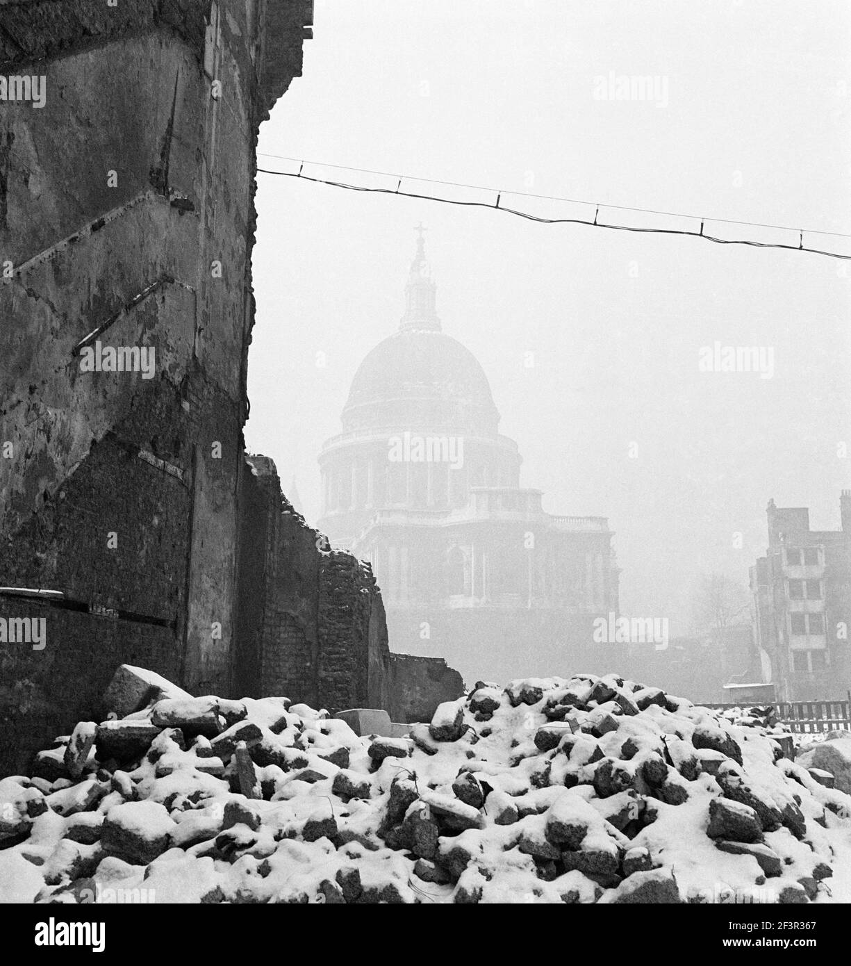 ST PAUL'S CATHEDRAL, London. The cathedral in mist with the snow-covered ruins of a bomb damaged building in the foreground.  Photographed by John Gay Stock Photo