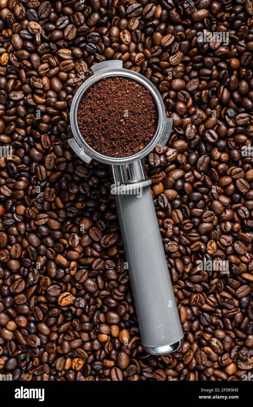 Foto Stock A portafilter with coffee beans, a tamper portafilter with  ground coffee, an espresso shot black table.