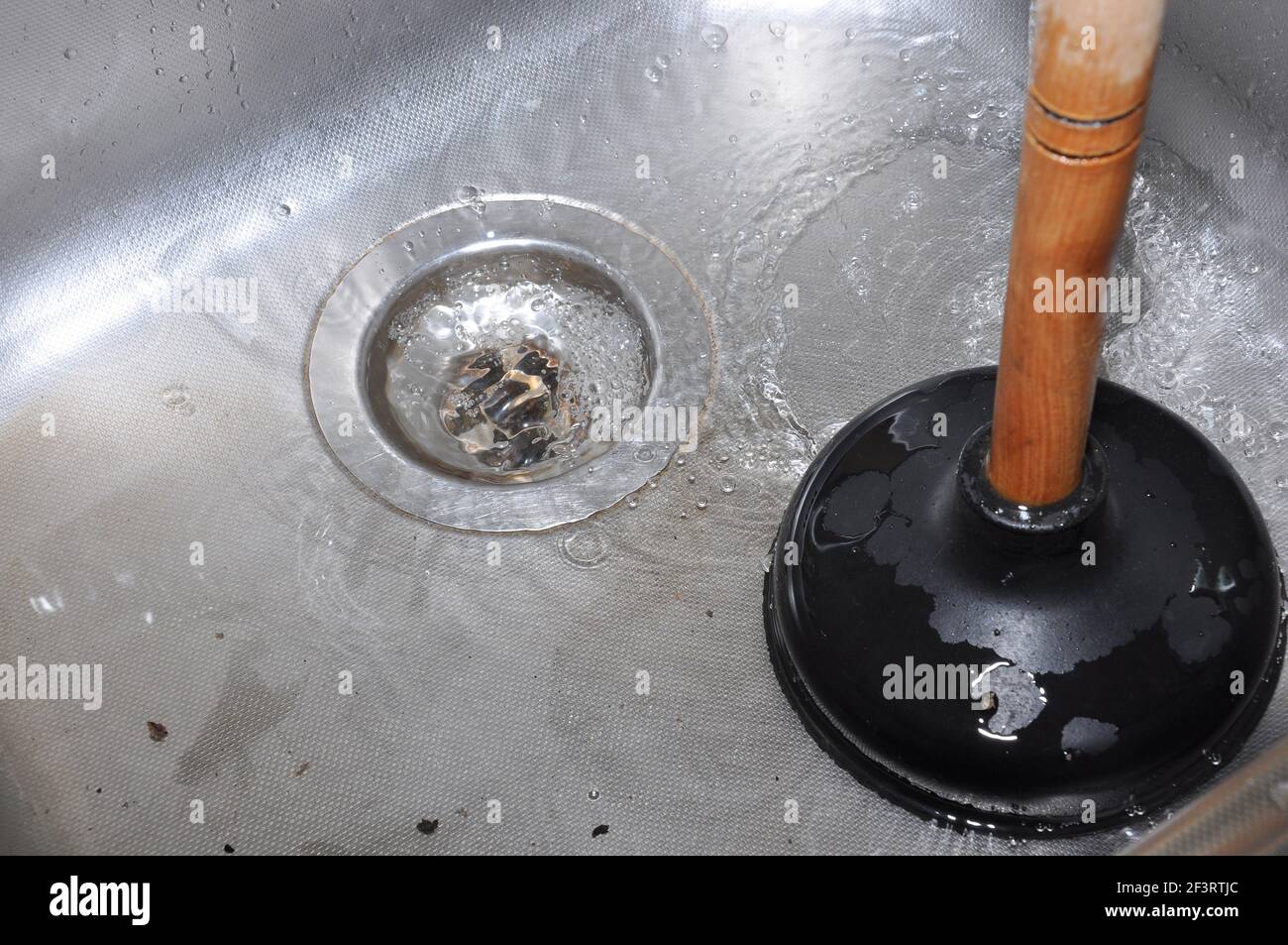 Plunger and clogged kitchen sink. Pipe cleaning concept. Sanitary engineering work Stock Photo