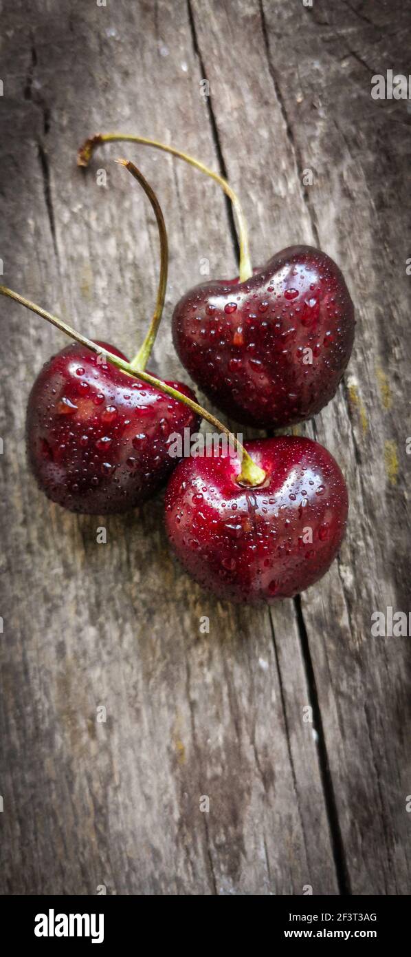 A vertical shot of ripe juicy cherries on a wooden sur Stock Photo - Alamy