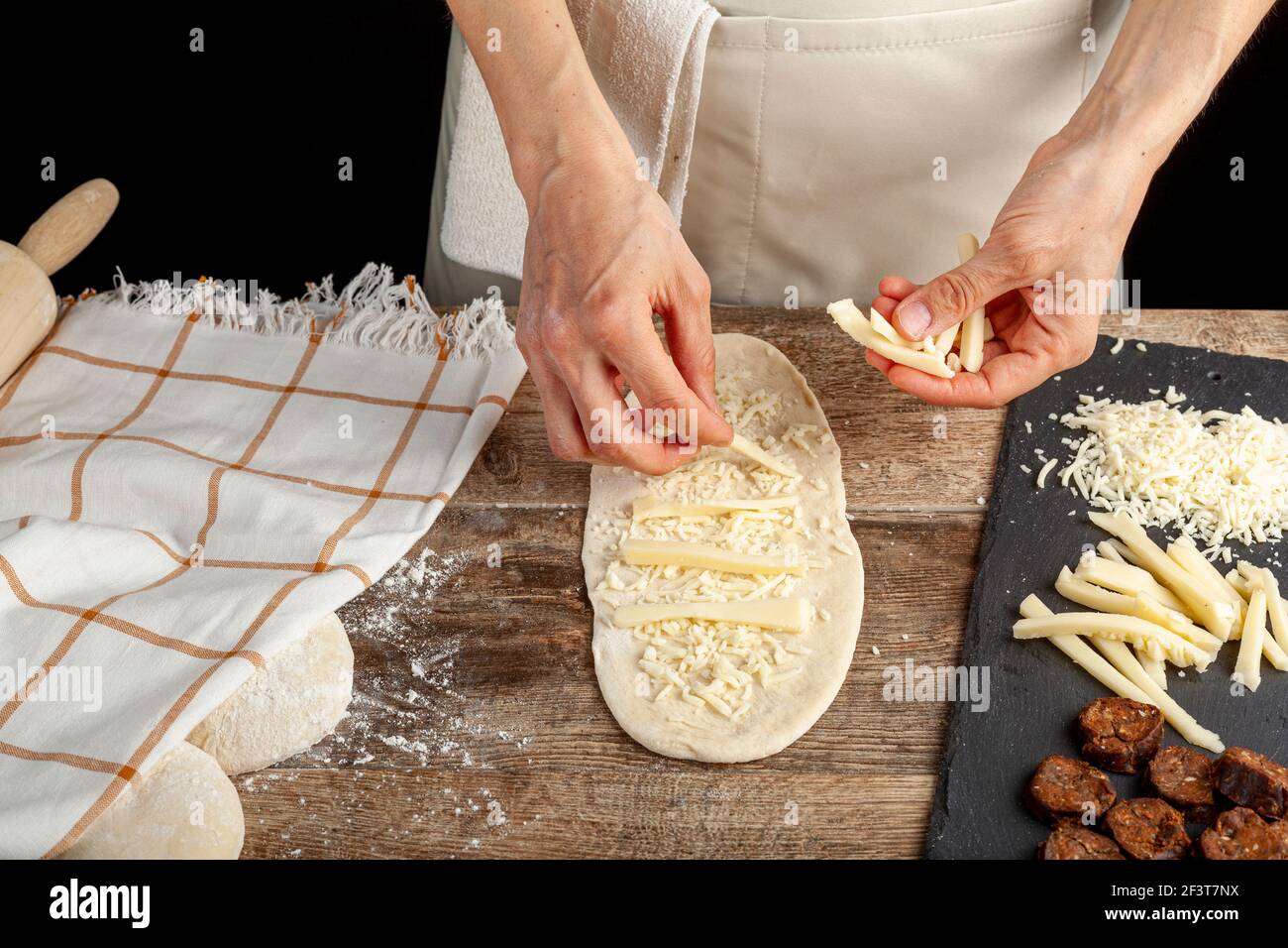 a flattened dough on wood kitchen countertop. A bread making concept image with loafs, cheese
