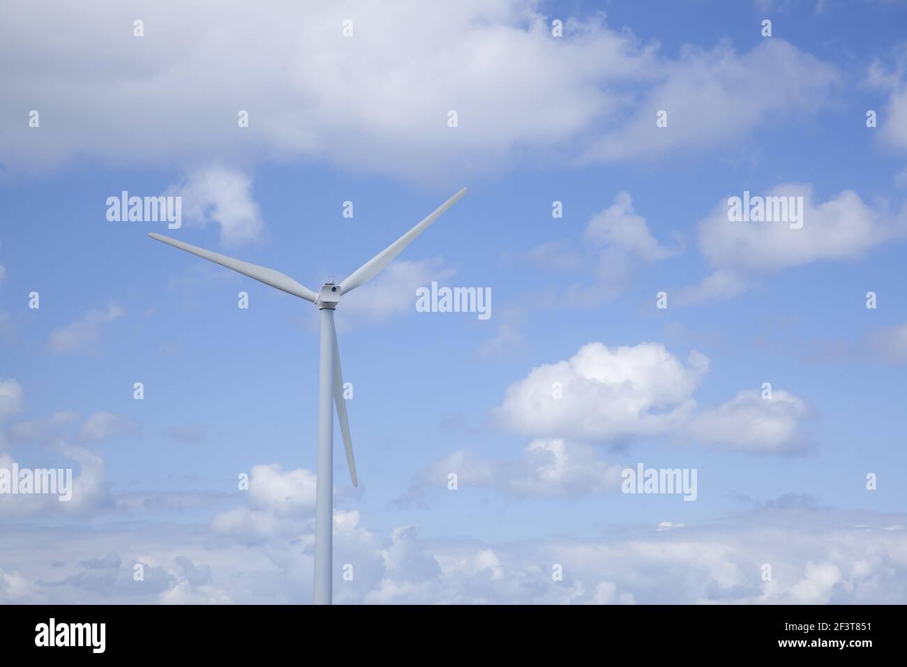 A wind turbine with a cloudy sky during the daytime Stock Photo - Alamy