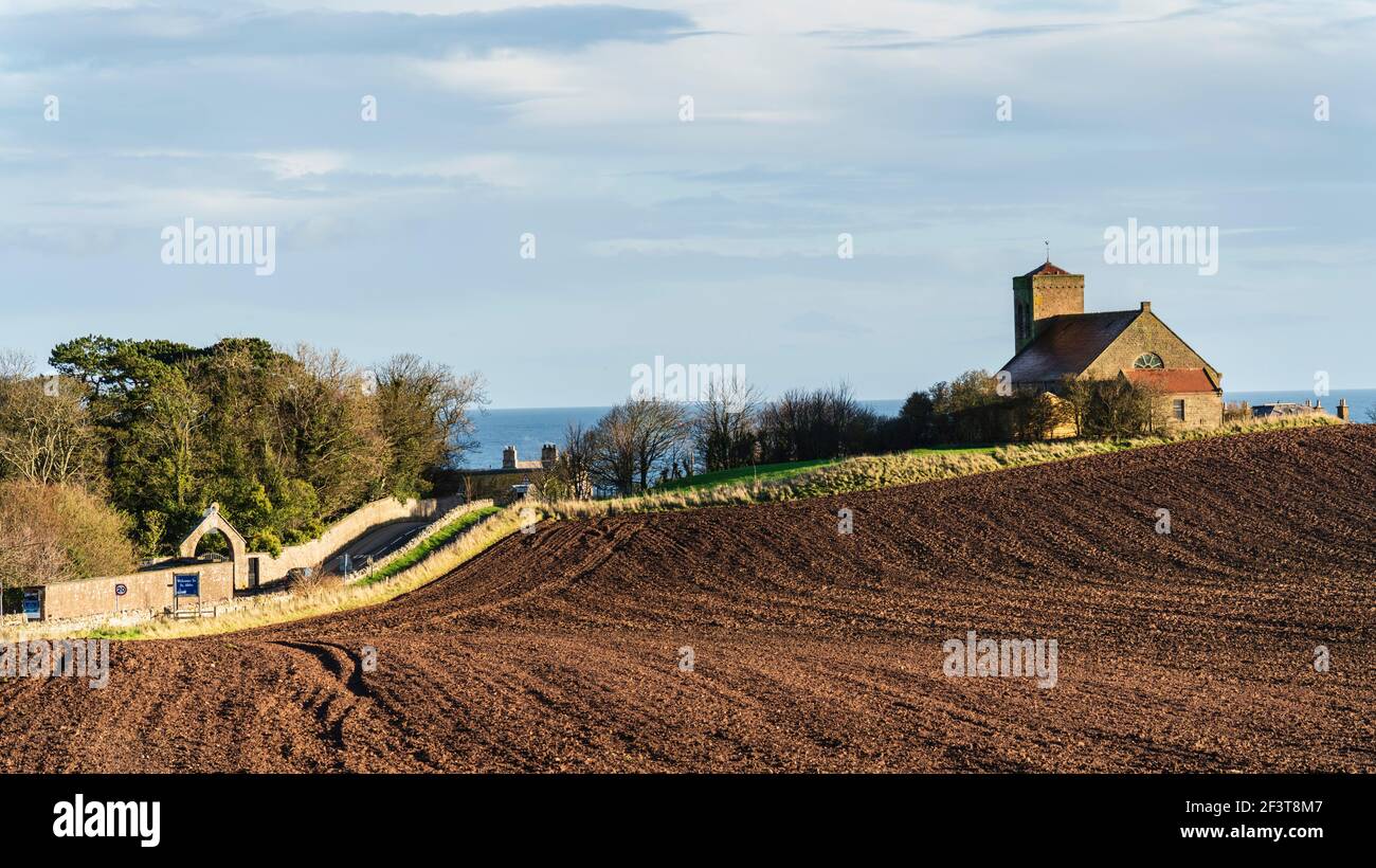 St Abbs, Berwickshire, Scotland - North Sea fishing village and nature reserve. Church and ploughed field. Stock Photo