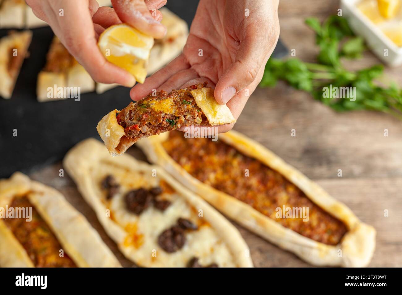 Kasarli sucuklu pide and kiymali pide are traditional Turkish flatbreads similar to pizza with meat and cheese toppings. They are served with lemon an Stock Photo