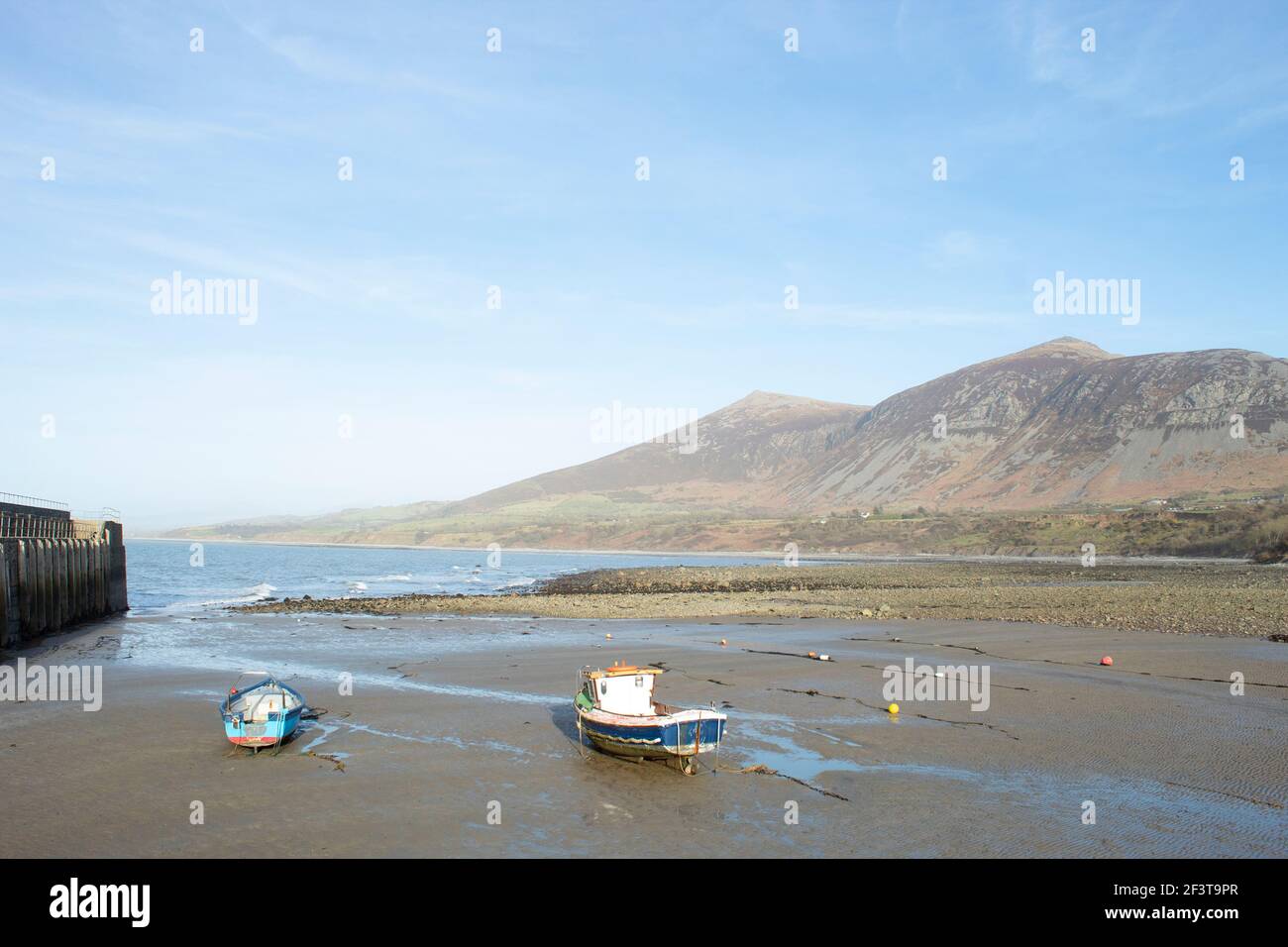 Trefor beach, Wales. Two small fishing boats at a secluded bay near Snowdonia on the Llyn Peninsula on a sunny, bright spring day. Peaceful placid cou Stock Photo
