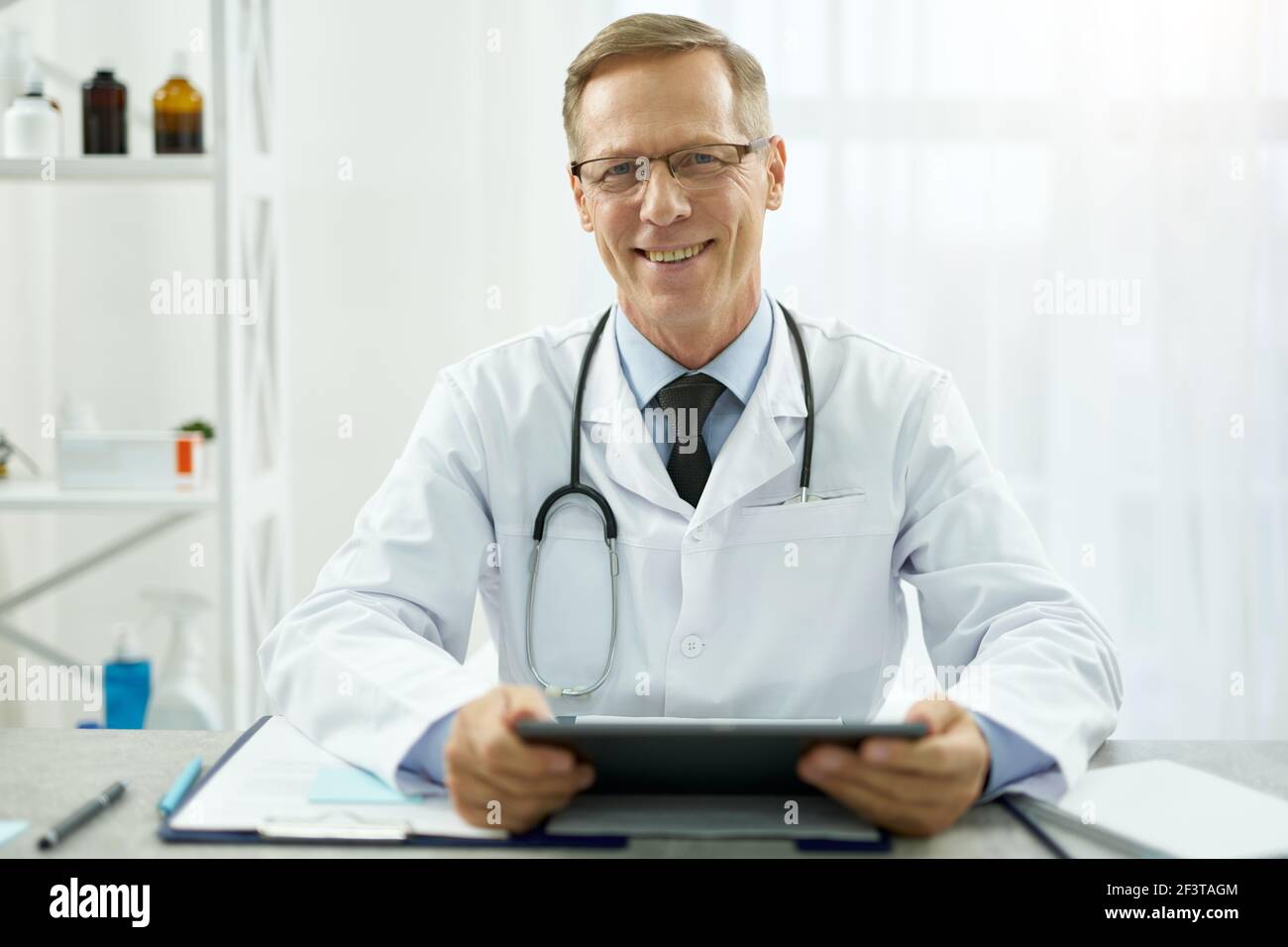 Cheerful male doctor using tablet computer at work Stock Photo