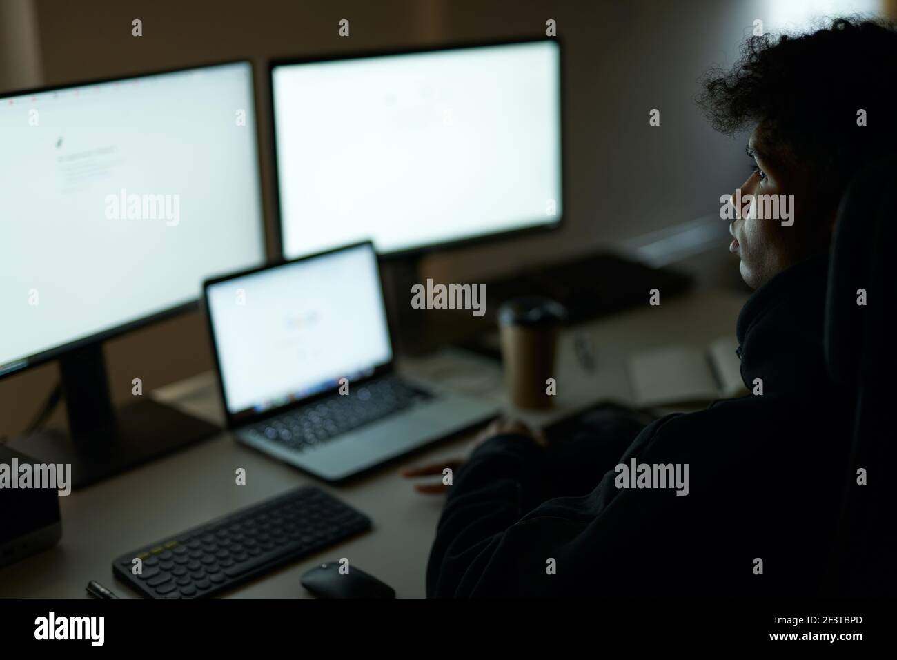 Be busy. Skilled specialist, guy sitting in front of many computer monitors, testing, finishing or debugging software Stock Photo