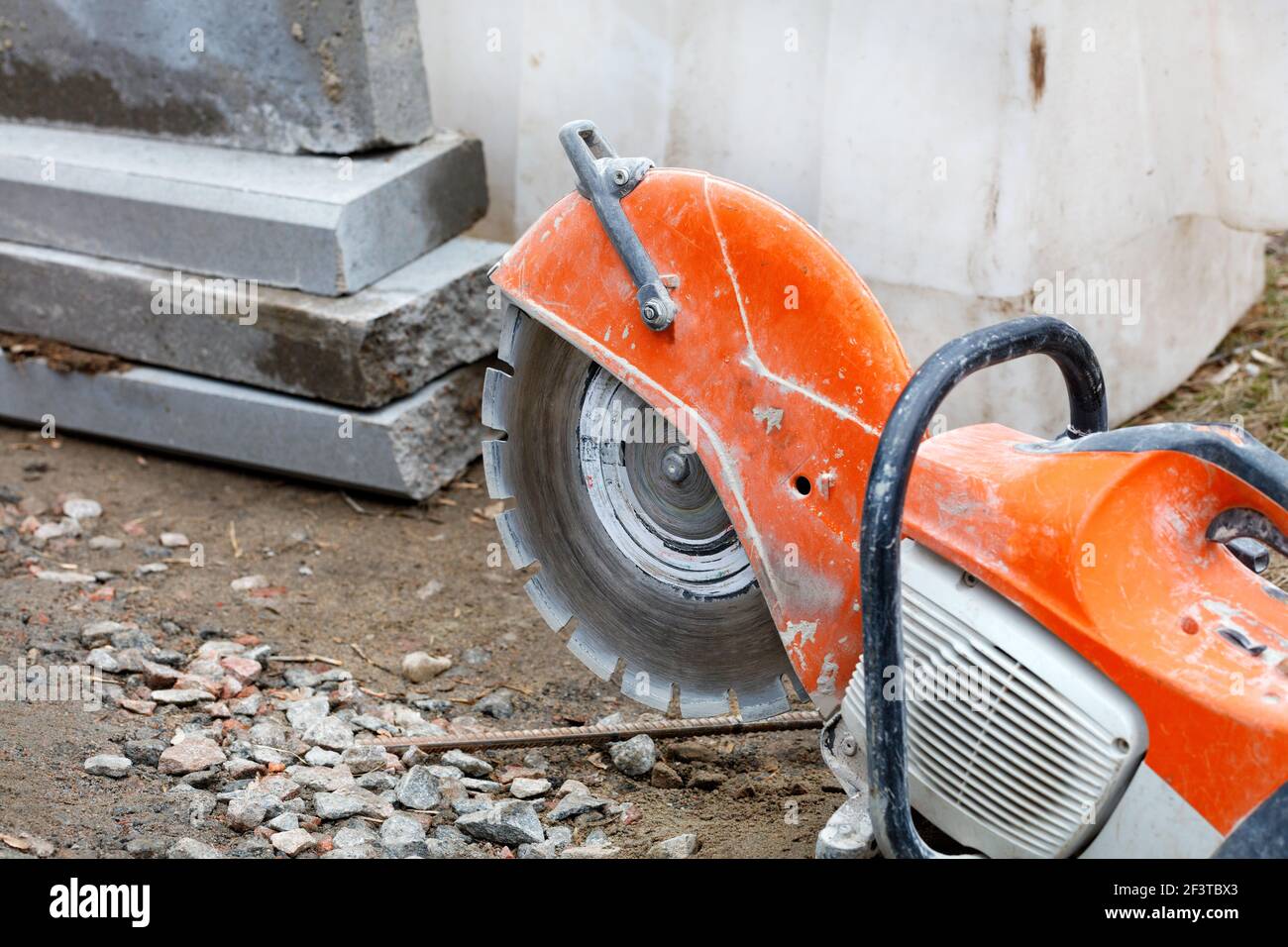 A worn bright orange gasoline cutter with a diamond cut off wheel