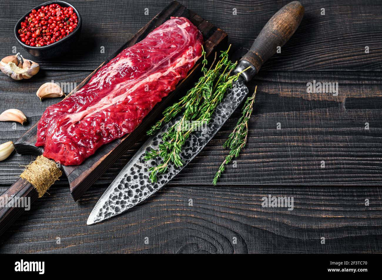 Raw Onglet Hanging Tender beef meat steak on a wooden cutting board. Black wooden background. Top view. Copy space Stock Photo