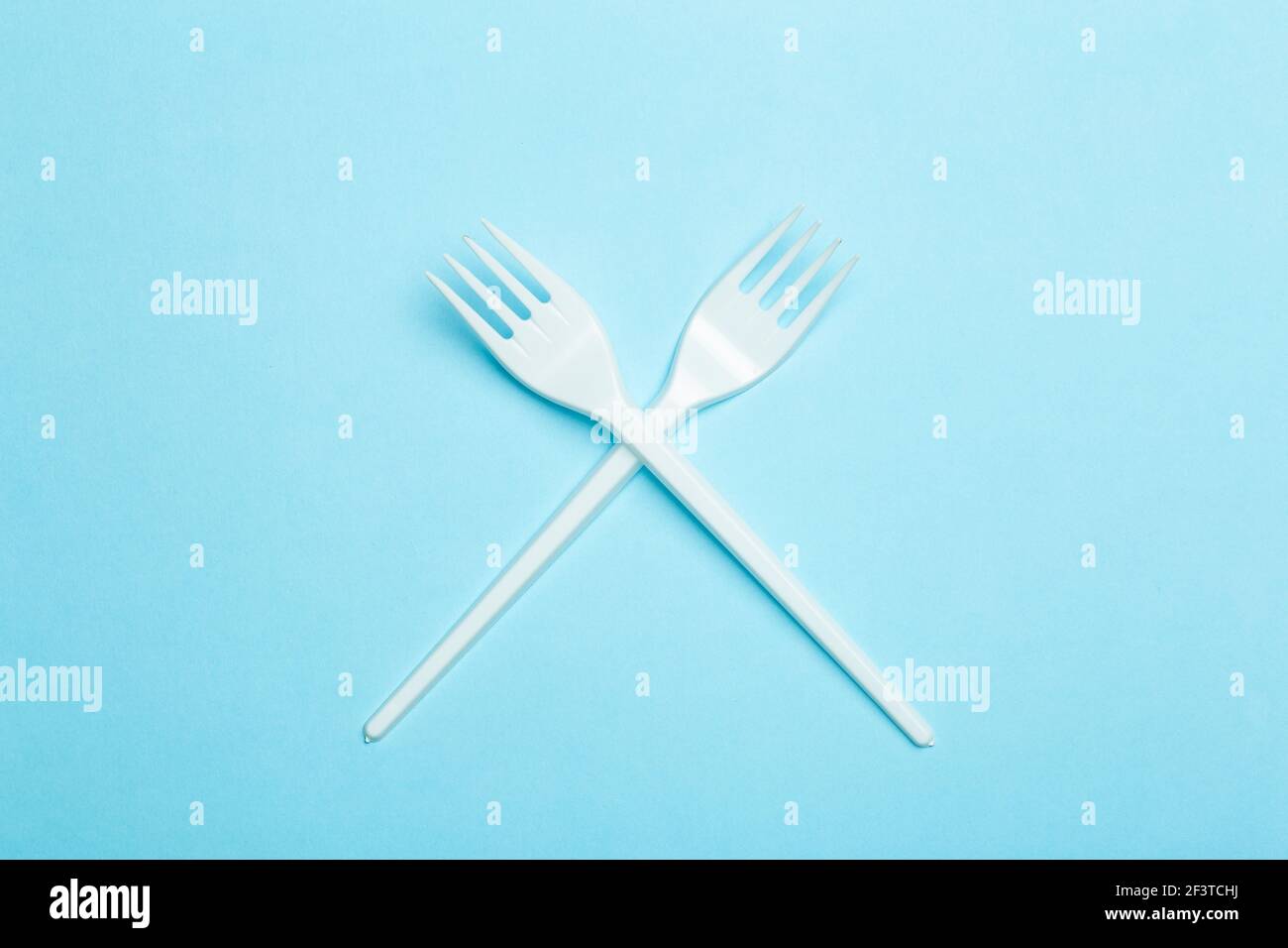 Plastic forks on a blue background. Plastic waste and pollution concept. Stock Photo