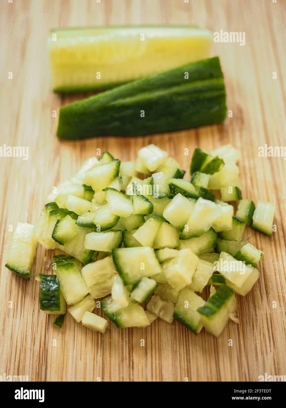 Cucumber cutted in dices over a wood table with rest of cucumber at