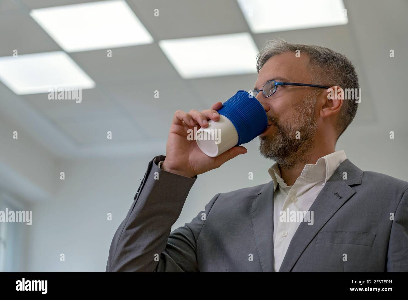 Businessman or Teacher Standing in Office During Coffee Time. Portrait of Mature Man With Cup of Coffee. Man Drinking Coffee. Stock Photo