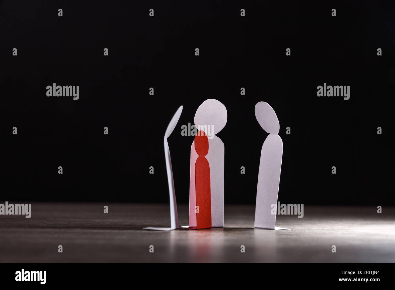 Child bullying concept with cutouts of little paper men on wooden table and dark background Stock Photo