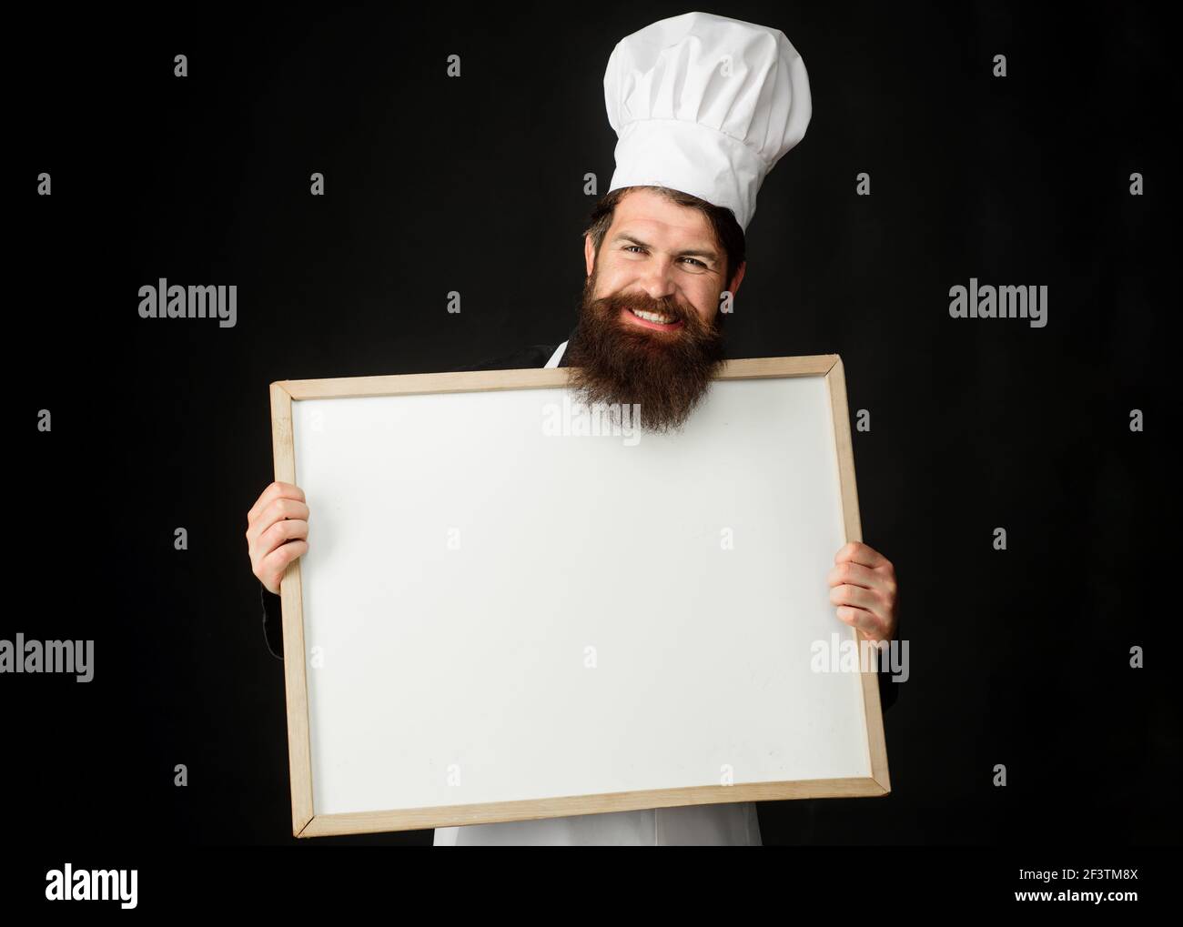 Master chef, baker or cook with menu blackboard. Cooking, culinary, advertisement and food concept. Stock Photo