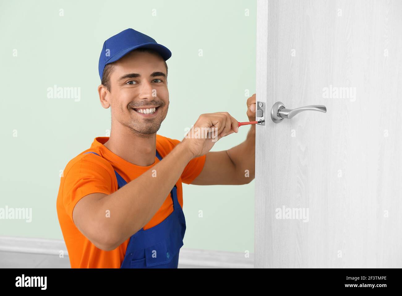 Worker repairing door lock with screwdriver Stock Photo
