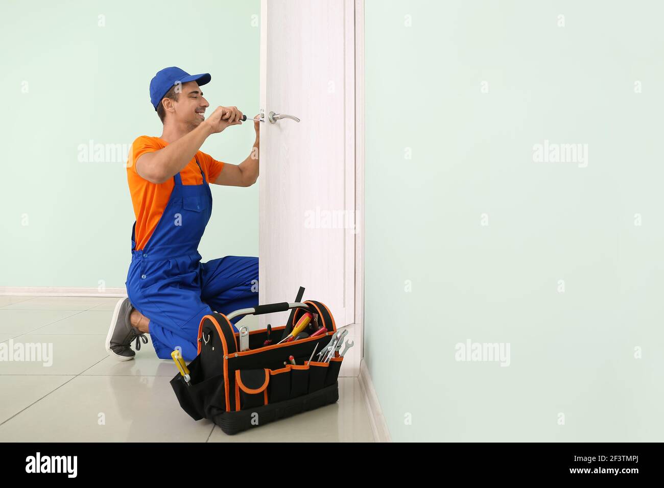 Worker repairing door lock with screwdriver Stock Photo
